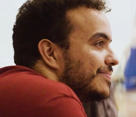 Homem de perfil com cabelo crespo e camiseta vermelha