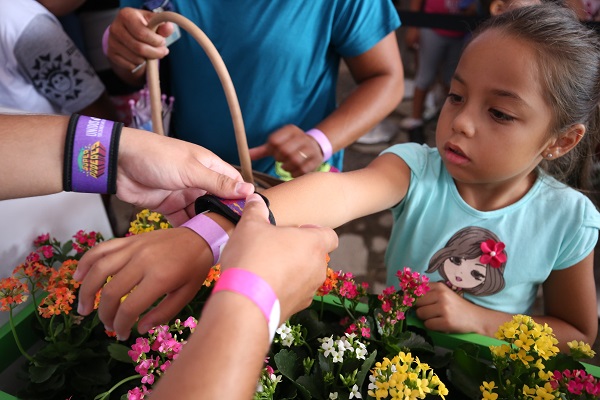 Mulher coloca uma pulseira no braço de uma criança.