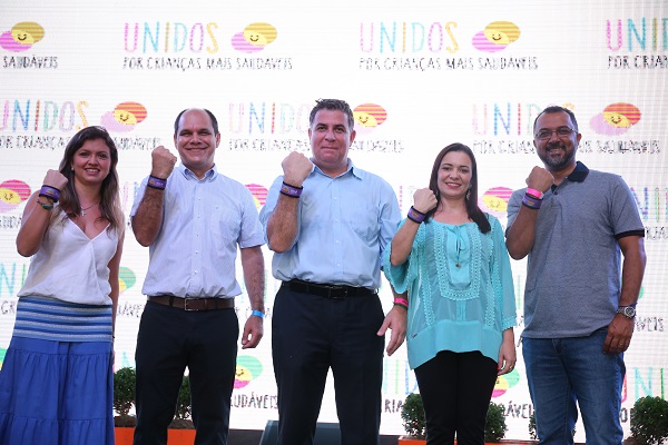 Três homens e duas mulheres posam para foto em um palco, com o braço em riste com o punho fechado.