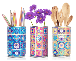 Três latas decoradas com desenhos que lembram azulejos coloridos. Dentro delas há lápis, flores e talheres de madeira.