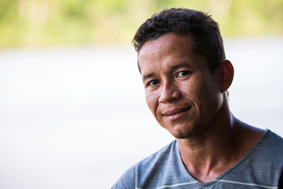 Homem de camiseta azul e cabelos pretos está sentado posando para a foto
